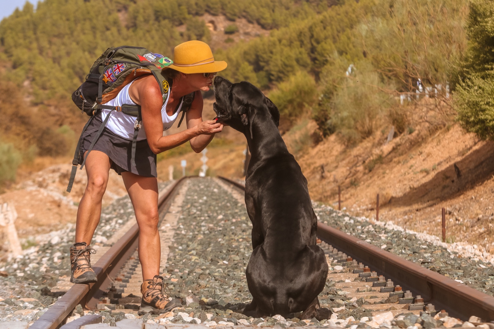 Mili Pérez besa a UX, su gran danés negro de 80 kilos, sentado junto a ella sobre las vías del tren